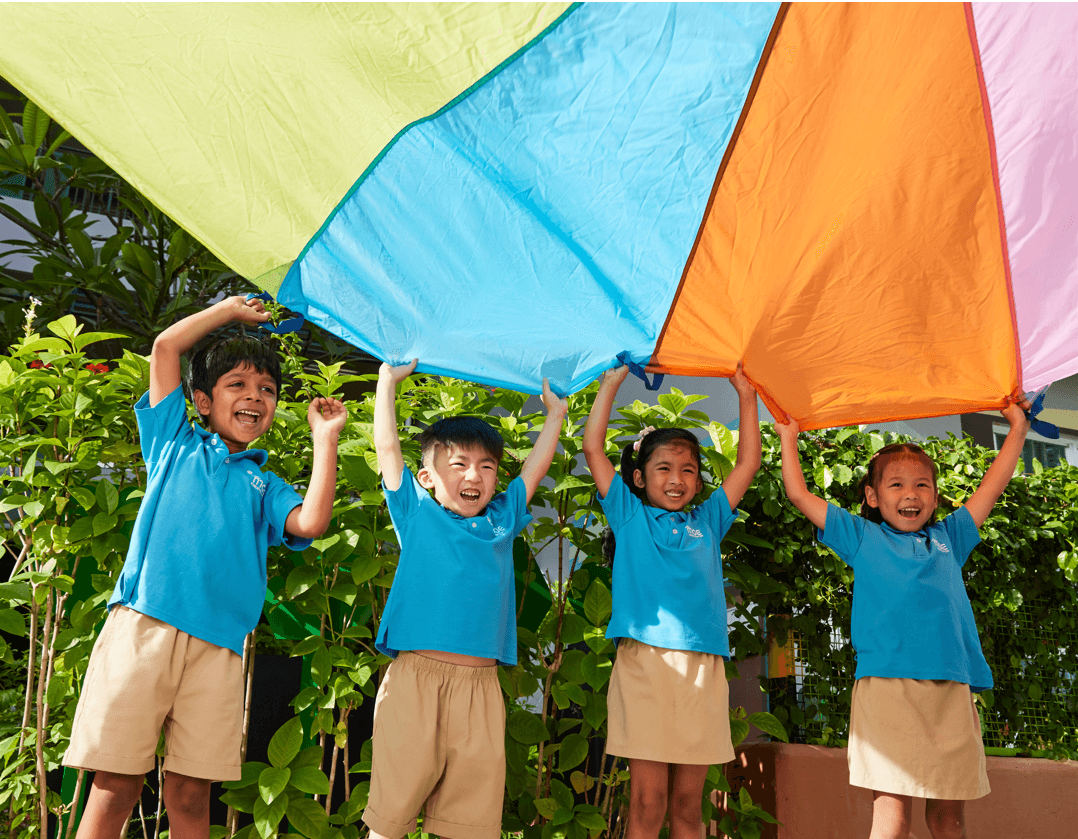 four children holding up a colourful fabric together